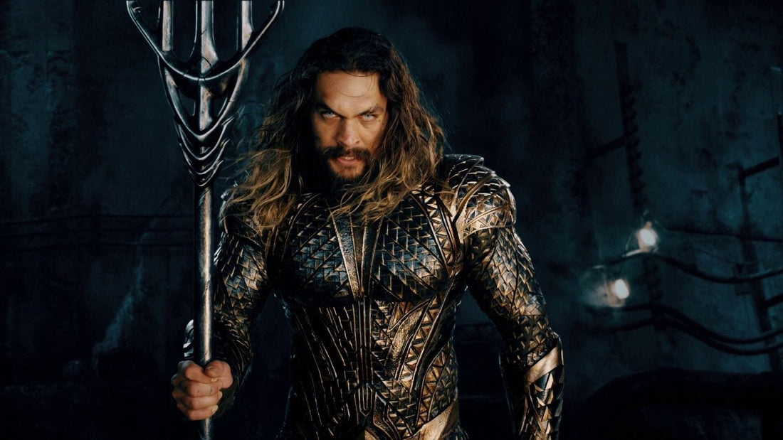 Jason Momoa en Aquaman, armure dorée et trident levé, regard vers toi, dans Justice League