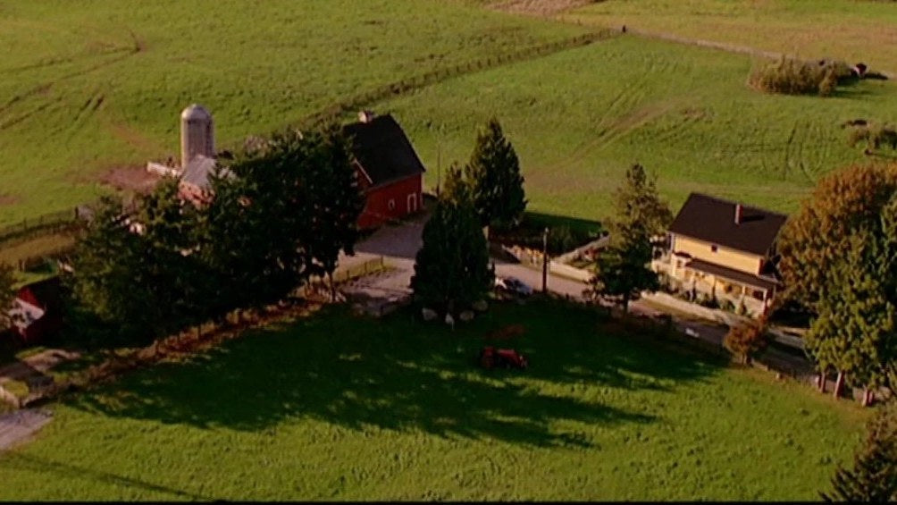 Vue aérienne de la ferme des Kent : maison, grange rouge et silo dans un champ, série Smallville