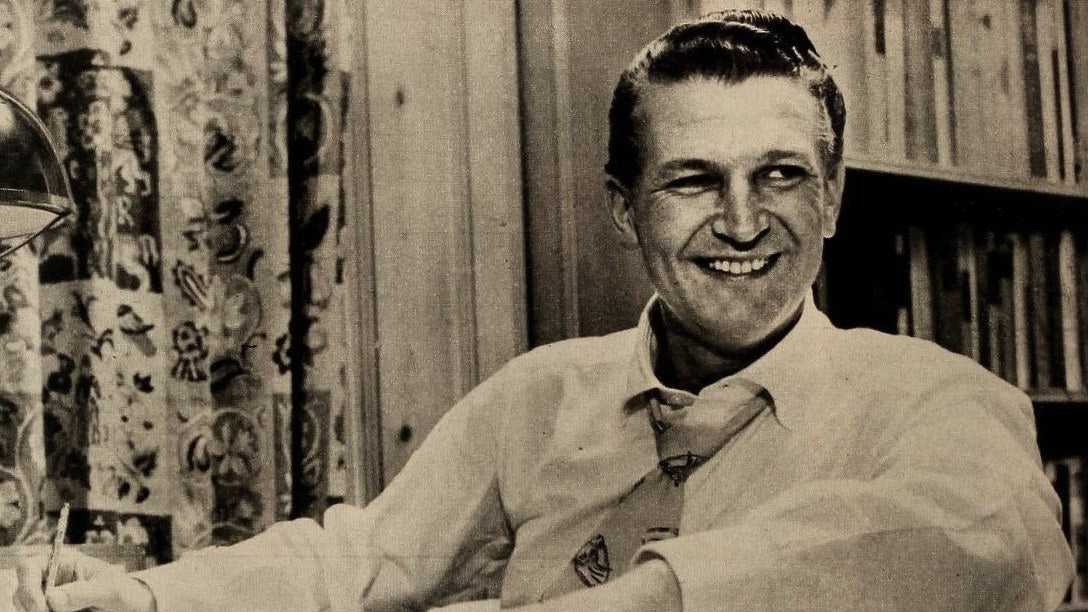 Bud Collyer, la voix de Superman dans le feuilleton radiophonique, souriant à son bureau sur une photo de 1953