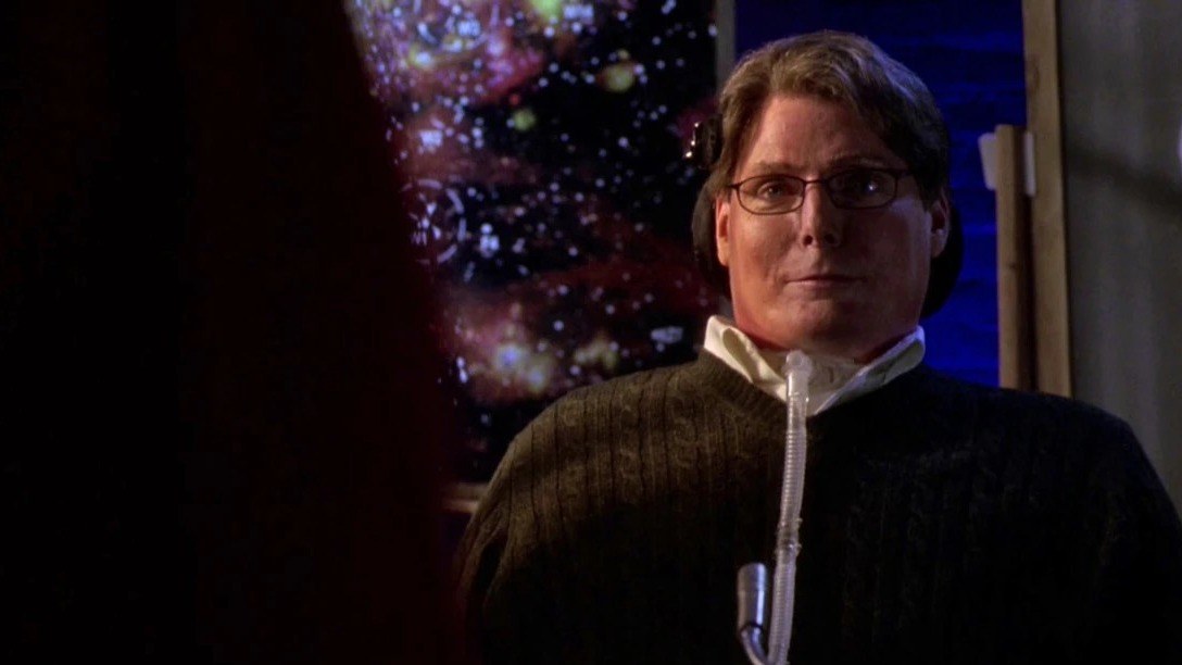 Christopher Reeve en Virgil Swann, lunettes et pull sombre, devant une image d'étoiles dans la série Smallville