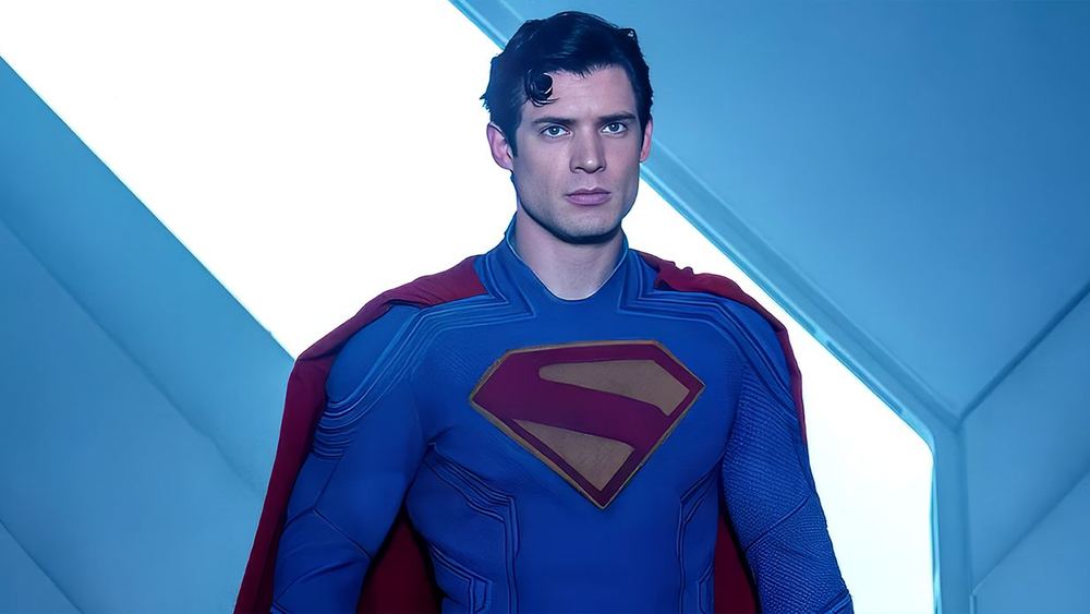 David Corenswet en Superman, costume bleu et cape rouge, sur un fond clair