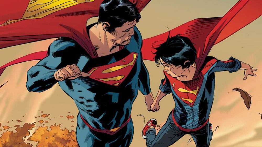 Superman et Jon Kent en costume volent côte à côte au-dessus d'un décor d'automne