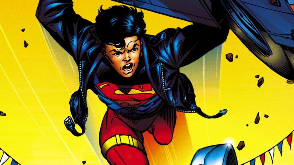 Superboy en blouson noir, blason S sur le torse, soulève une voiture