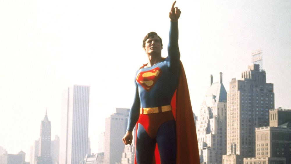 Christopher Reeve en Superman, index levé, devant les tours de Metropolis