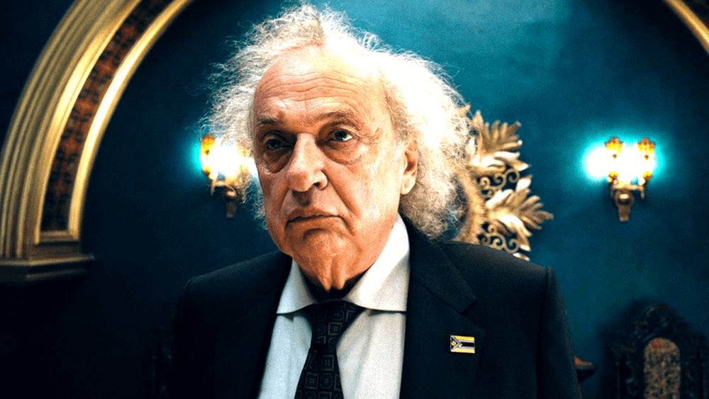 Zlatko Burić en Vasil Ghurkos, costume sombre et cheveux blancs, dans Superman 2025